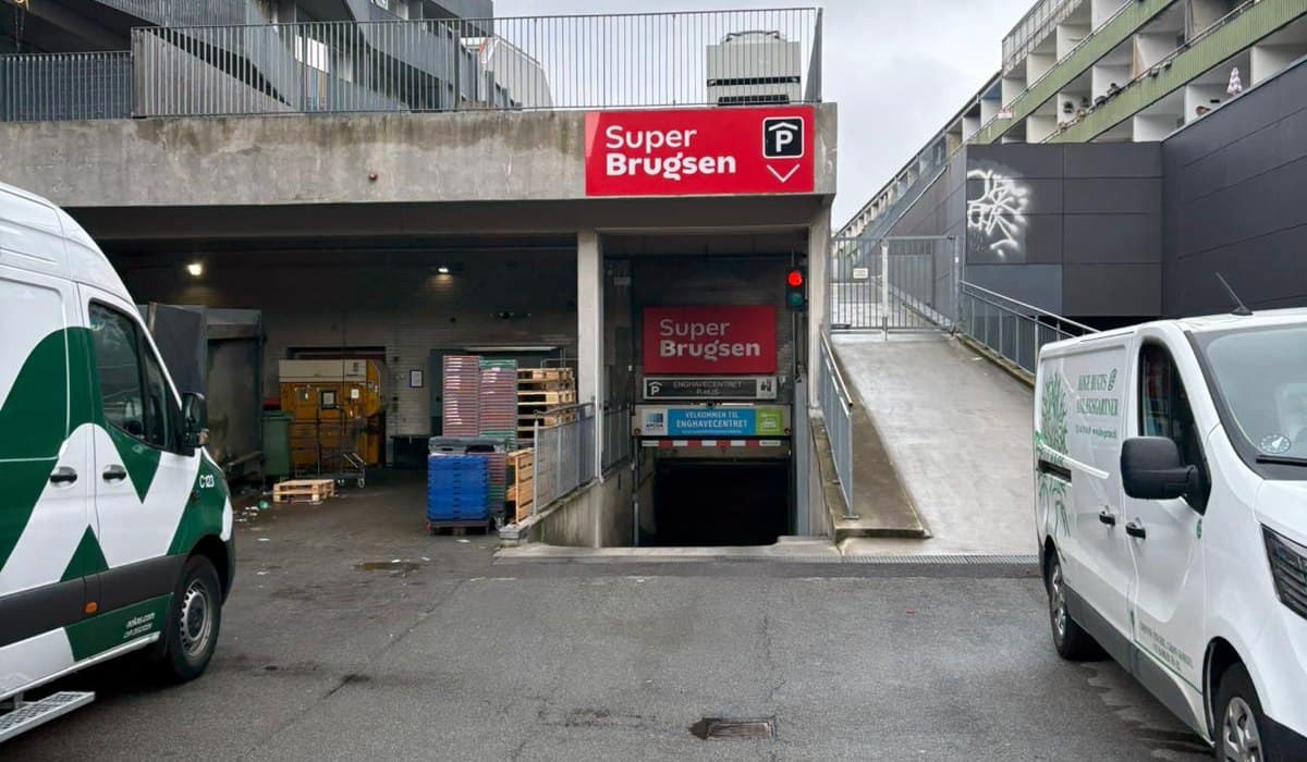 Indkørsel til et supermarkeds p-hus med parkeringsskilt over rampen.