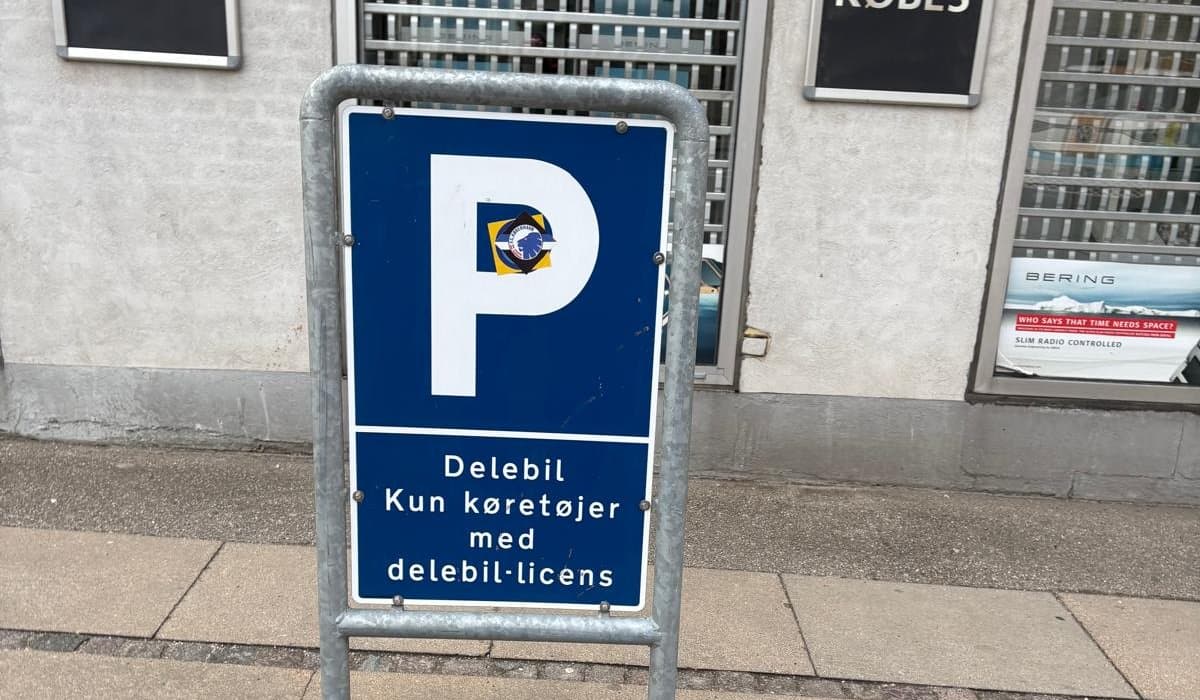 Blåt p-skilt på et fortov i København med teksten Delebil, kun køretøjer med delebil-licens.