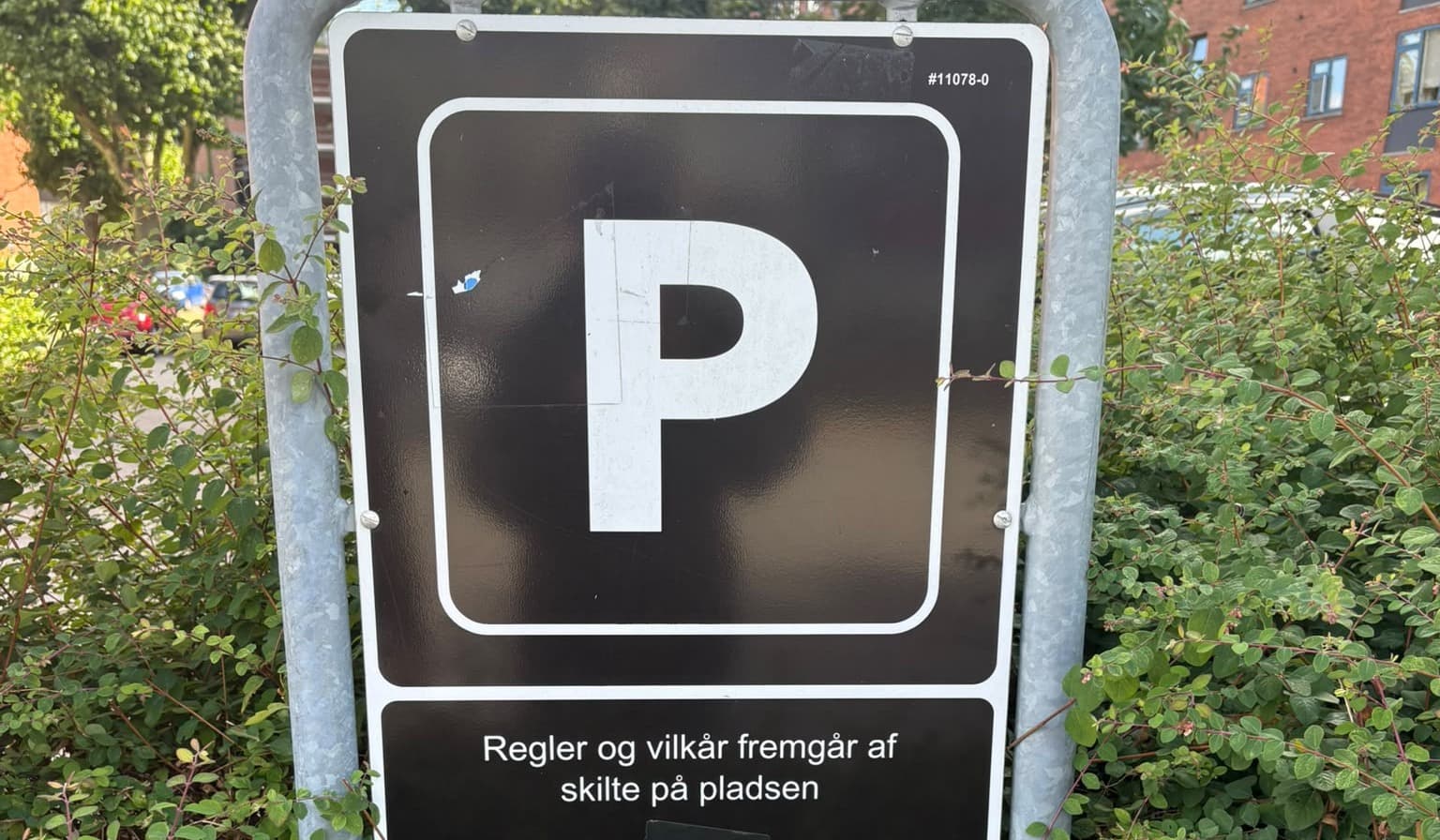 Sort privat parkeringsskilt med et hvidt P og teksten "Regler og vilkår fremgår af skilte på pladsen".