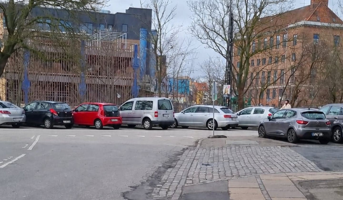 Illustrationsfoto af parkerede biler ved et vejkryds i en dansk bygade.