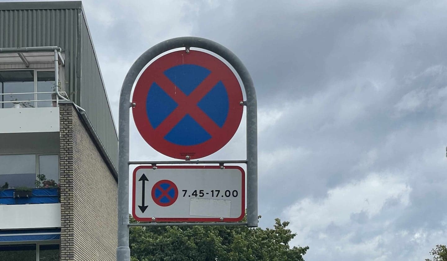 Skilt med tidsbegrænset standsningsforbud langs en dansk boligvej.