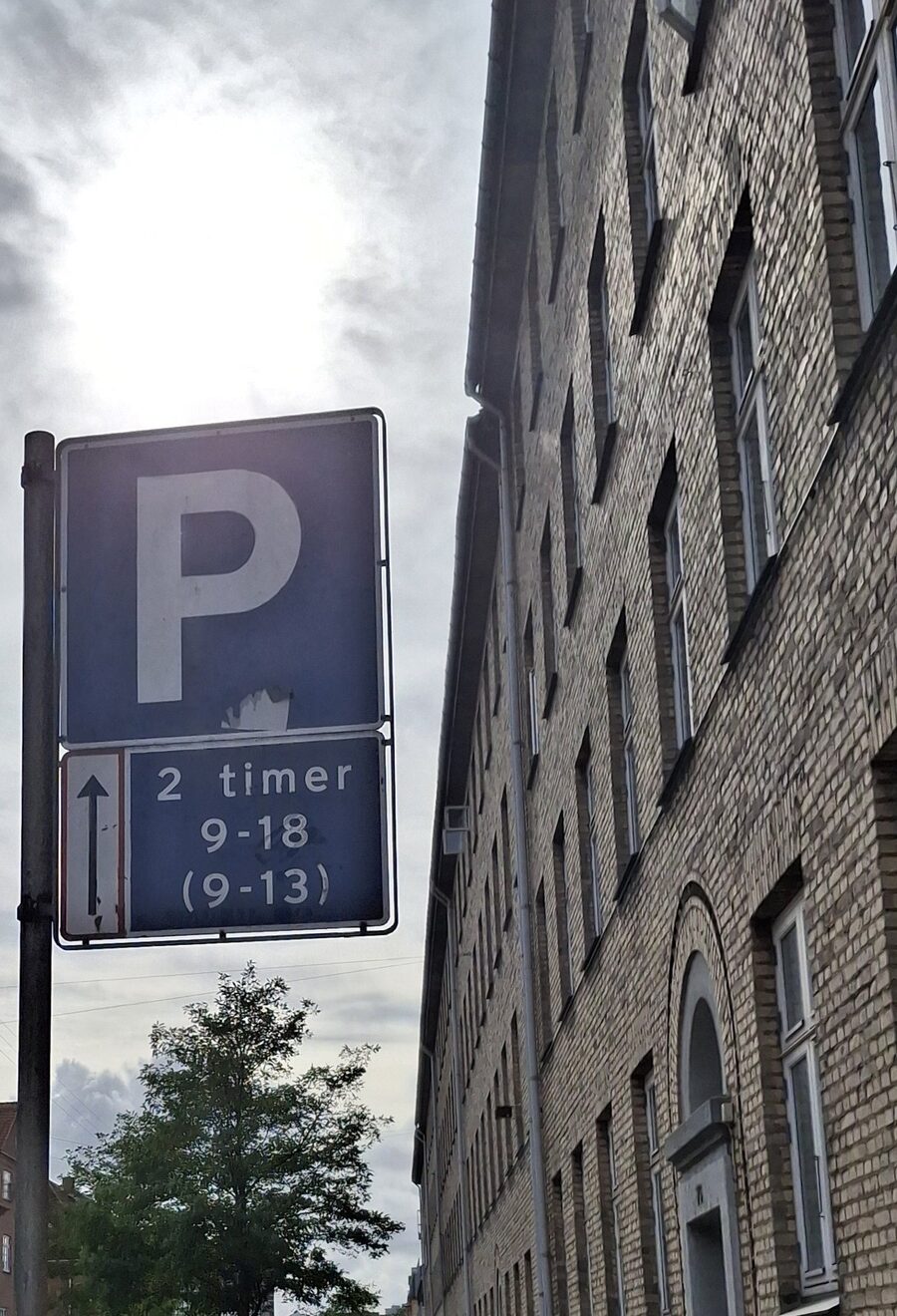 P-skilt med undertavle "2 timer 9-18 (9-13)" og pil — typisk tidsbegrænset parkering i København